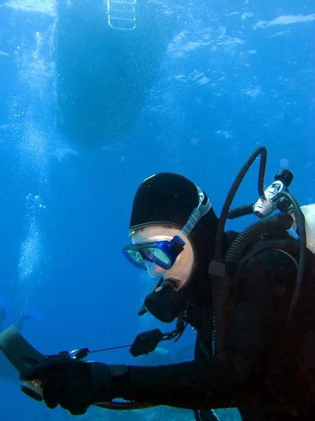 Scuba Diver Controllare i calibri sotto la barca — Foto Stock