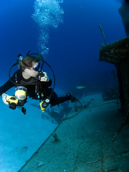Fotógrafo submarino mirando un barco hundido —  Fotos de Stock