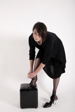 Ayakkabılarını giyen siyah elbiseli genç esmer kadın