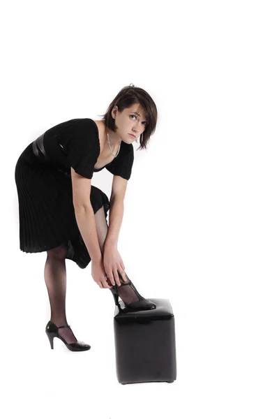 Young brunette woman in black dress wearing her shoes — Stock Photo, Image