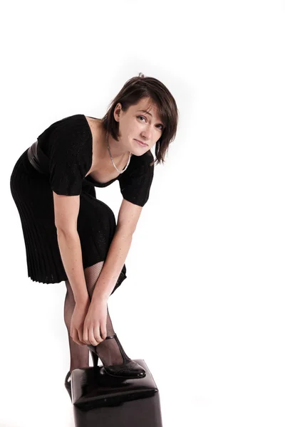 Młoda brunetka kobieta w czarnej sukience jej butach — Zdjęcie stockowe