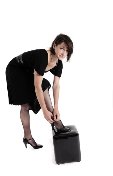 Young brunette woman in black dress wearing her shoes — Stock Photo, Image