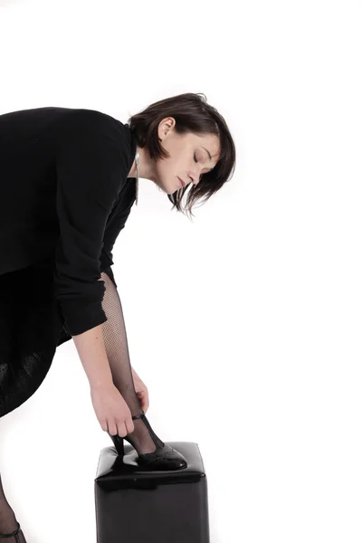 Young brunette woman in black dress wearing her shoes — Stock Photo, Image