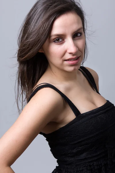 Beautiful young woman smiling, against a gray background — Stock Photo, Image