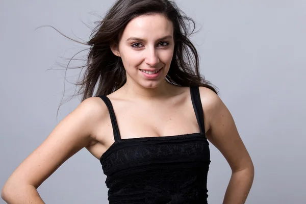 Beautiful young woman smiling, against a gray background — Stock Photo, Image