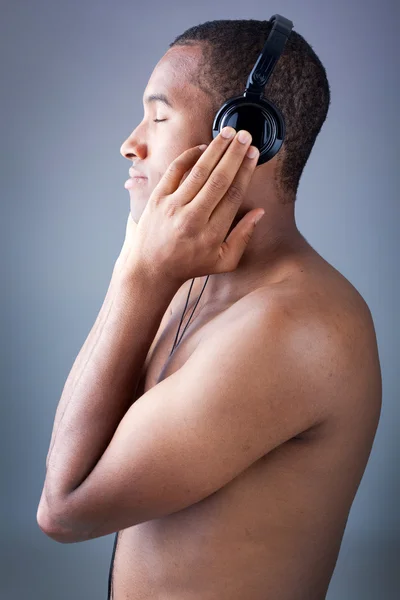 Ung svart man lyssnar på musik i hörlurar — Stockfoto