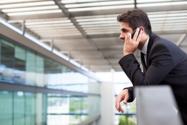 Modern ofiste cep telefonuyla konuşan genç bir iş adamı.
