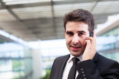 Modern ofiste cep telefonuyla konuşan genç bir iş adamı.