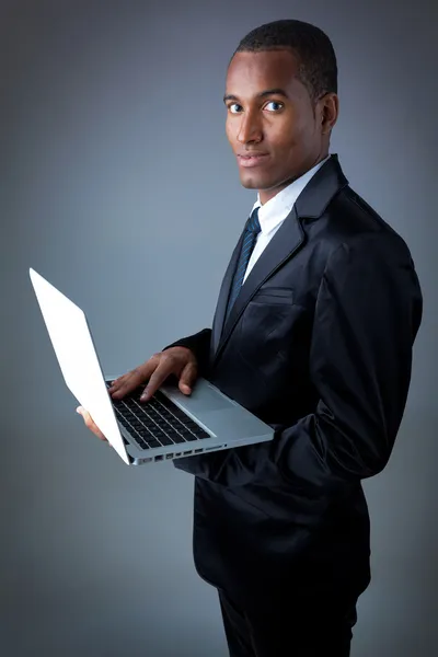 Africano jovem homem de negócios com laptop em fundo cinza — Fotografia de Stock