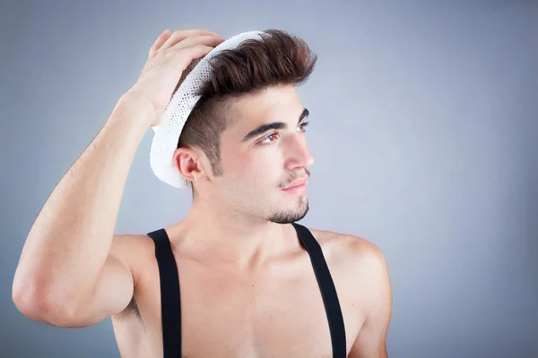 Portrait d'un beau jeune homme au chapeau sur fond gris — Photo