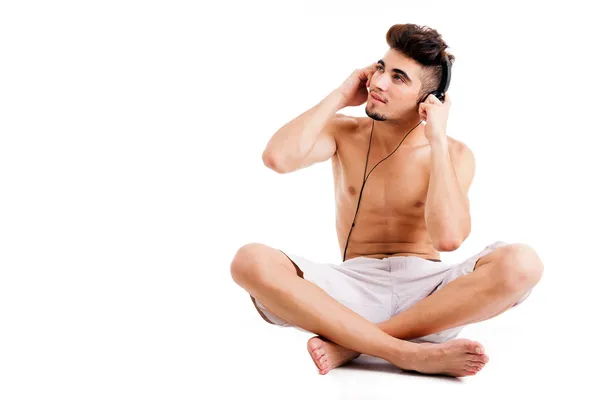 Bar överkropp ung man sitter på golvet och lyssnar på musik, iso — Stockfoto