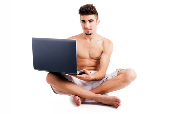 Młody człowiek siedzi na podłodze i za pomocą laptopa, na w tle — Zdjęcie stockowe