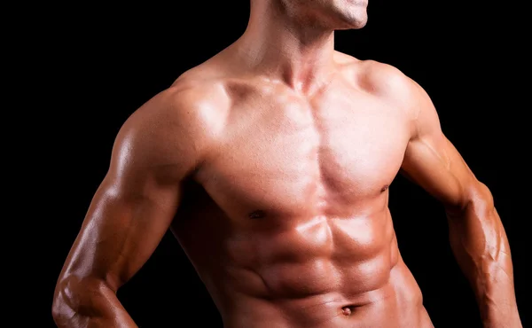 Young muscular man with beautiful torso agaisnt black background — Stock Photo, Image