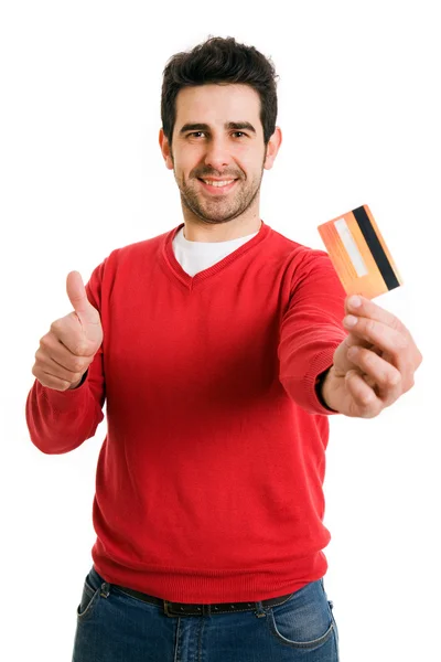 Happy smiling young man holding a credit card and gives thumb up — Stock Photo, Image