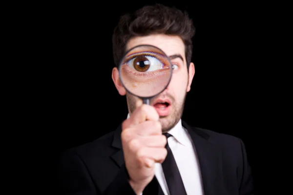 Portrait of a handsome young man looking through a magnifying gl — Stock Photo, Image