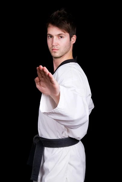 Mladý muž v kimonu se bojová umění cvičení na černém pozadí — Stock fotografie