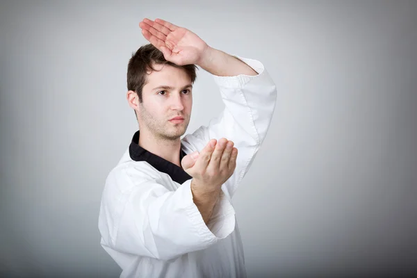 Joven practicando artes marciales sobre fondo gris —  Fotos de Stock