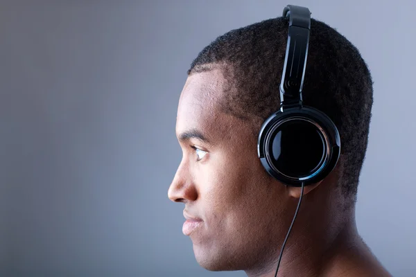 Profil africké člověka poslouchat hudbu na šedém pozadí — Stock fotografie