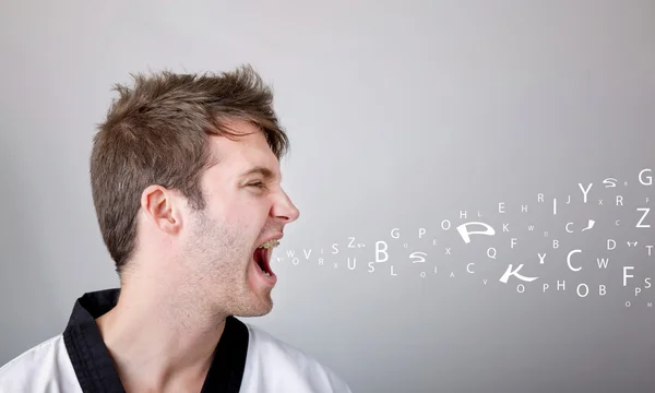 Young martial arts man shouting over gray background — Stock Photo, Image