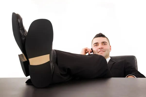 Sorridente giovane uomo d'affari rilassante alla scrivania dell'ufficio e parlando o — Foto Stock