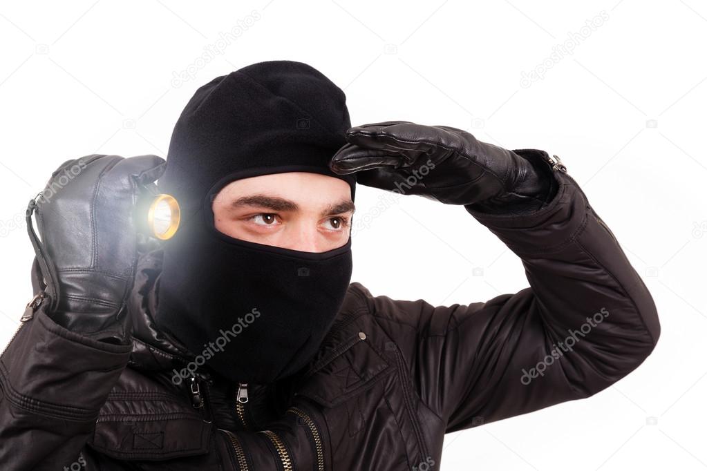 Thief with flashlight isolated in white