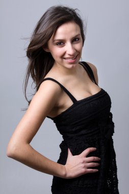 güzel bir genç kadın gülümseyerek, gri bir arka planı