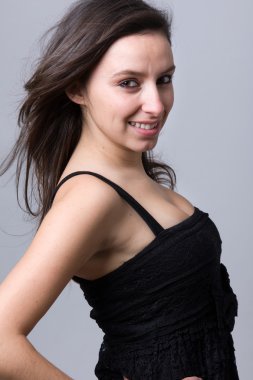 güzel bir genç kadın gülümseyerek, gri bir arka planı