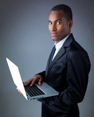 Afrikalı-Amerikalı genç iş adamı ile laptop gri arka plan üzerinde