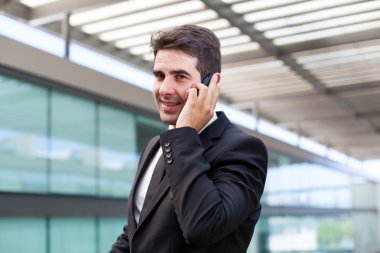 Modern ofiste cep telefonuyla konuşan genç bir iş adamı.