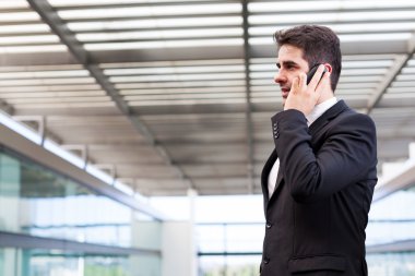 Modern ofiste cep telefonuyla konuşan genç bir iş adamı.