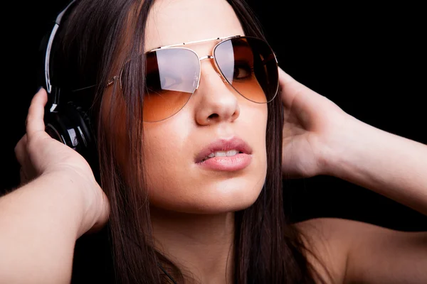 Beautiful young woman listening to music with headphones on black background — Stock Photo, Image