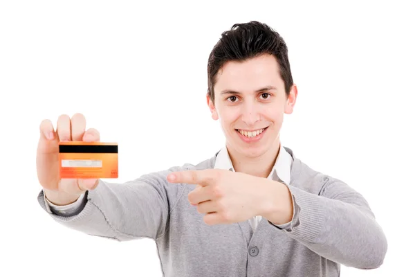 Happy smiling young man holding a credit card and pointing isolated on white background — Stock Photo, Image