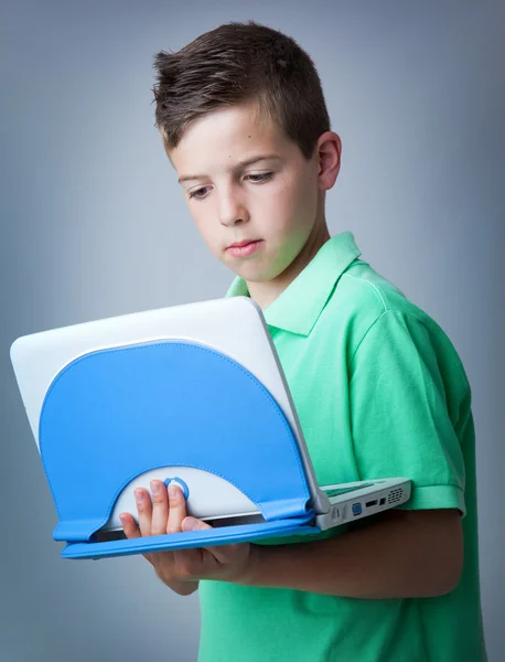 Niño pequeño con portátil contra fondo gris — Foto de Stock