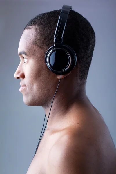 Joven hombre negro escuchando música en auriculares — Foto de Stock