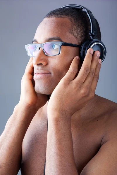 年轻的黑人男子，听听音乐用耳机在灰色背景 — 图库照片