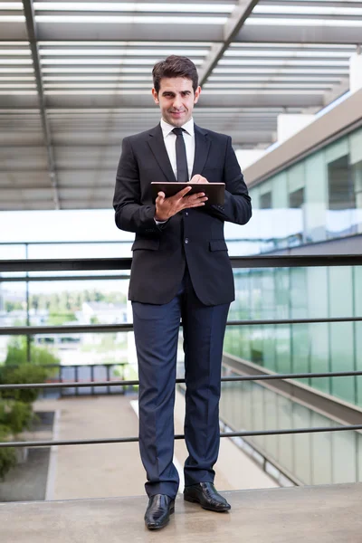 Улыбающийся молодой бизнесмен, использующий свой цифровой планшет в офисе — стоковое фото
