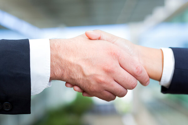 Мужчина и женщина пожимают друг другу руки в офисе
