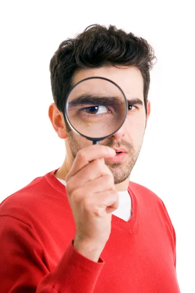 Portrait of young man looking through a magnifying glass over white background — Stock Photo, Image