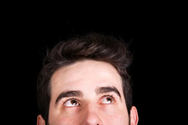 Young handsome man looking up, against black background — Stock Photo, Image