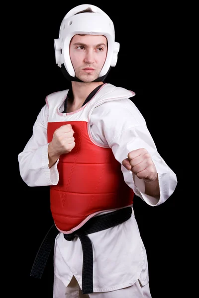 A fiatalember a taekwondo fokozatban harcra kész. fekete háttér. — Stock Fotó