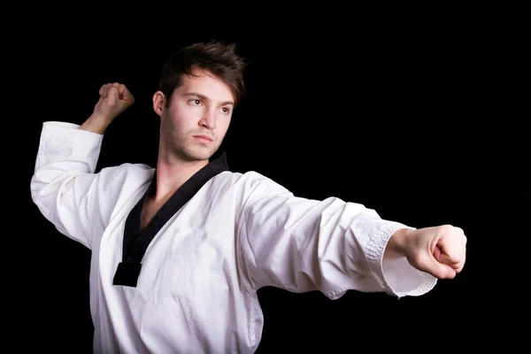 Jovem praticando artes marciais contra fundo preto — Fotografia de Stock