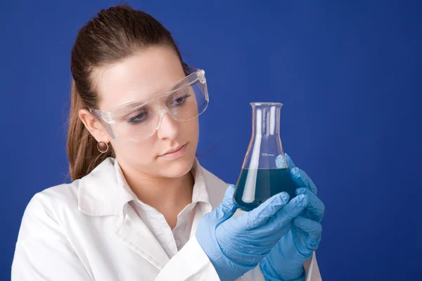 Young female researcher against blue background — Stock Photo, Image