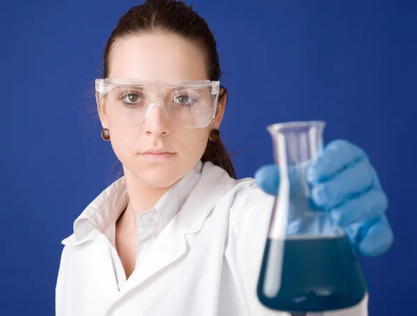 Jonge vrouwelijke onderzoeker tegen blauwe achtergrond — Stockfoto