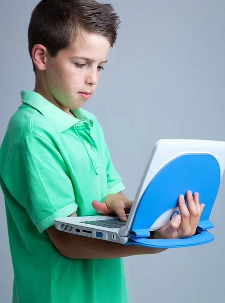 Menino com laptop no fundo cinza — Fotografia de Stock