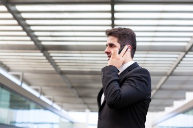 Modern ofiste cep telefonuyla konuşan genç bir iş adamı.