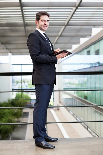 Smiling young businessman using his digital tablet at the office — Stock Photo, Image