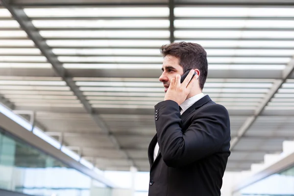 Joven hombre de negocios hablando por teléfono celular en la oficina moderna —  Fotos de Stock