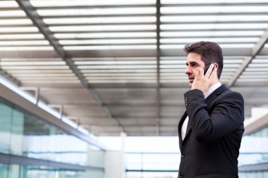Modern ofiste cep telefonuyla konuşan genç bir iş adamı.