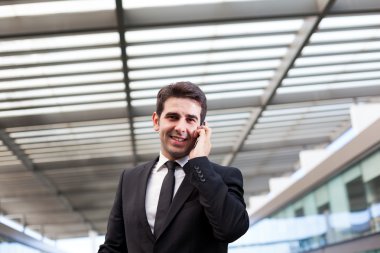 Modern ofiste cep telefonuyla konuşan genç bir iş adamı.