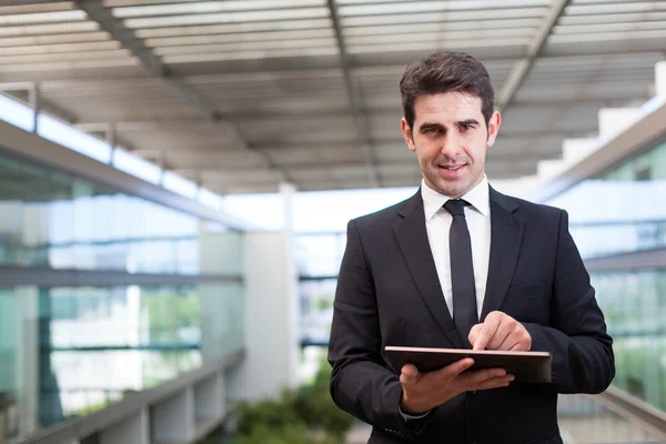 ofiste onun dijital tablet kullanarak gülümseyen genç işadamı